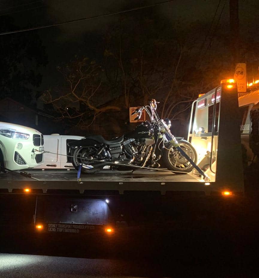 A Harley being towed by a truck late at night.