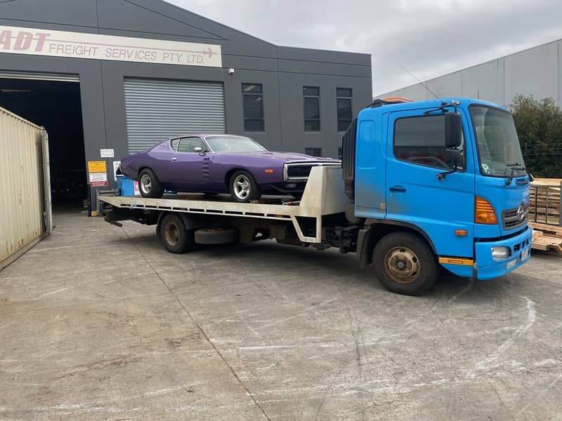 A tow truck transporting a classic car.