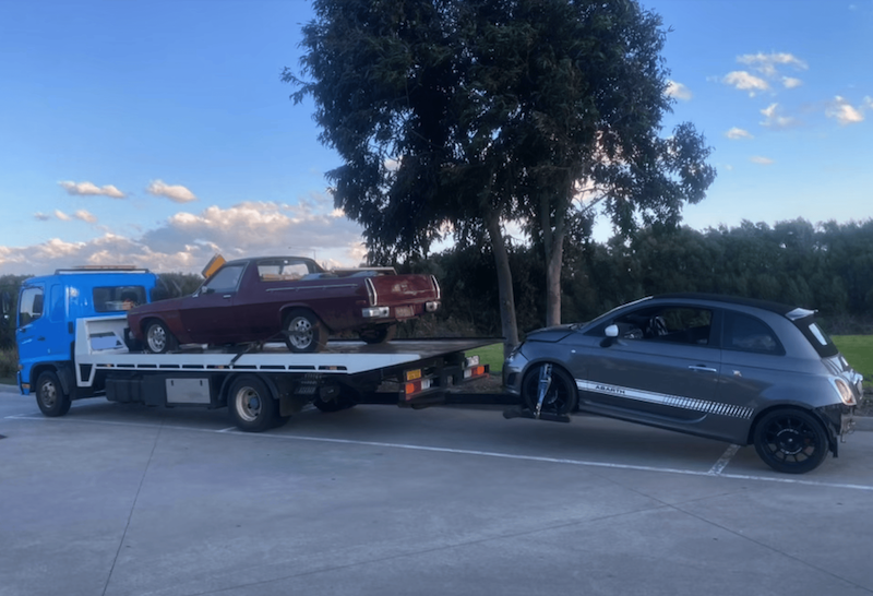 A tow truck towing two cars a long distance in Melbourne.