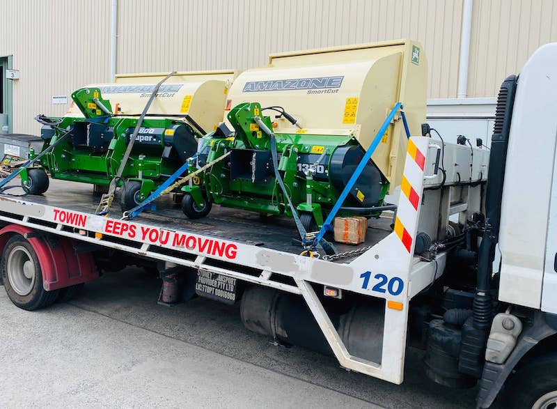 Machinery being transported by a tilt tray tow truck near Lalor.