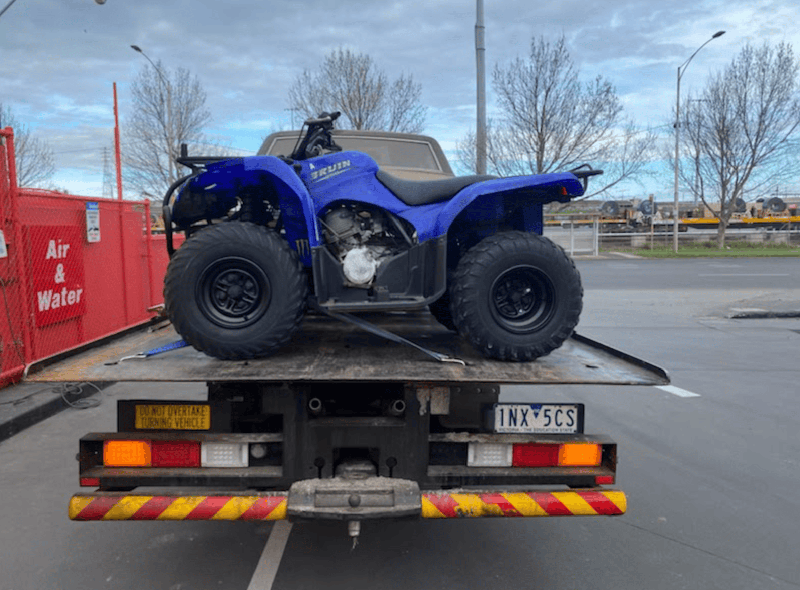 A quad bike being towed a long distance on a tow truck.