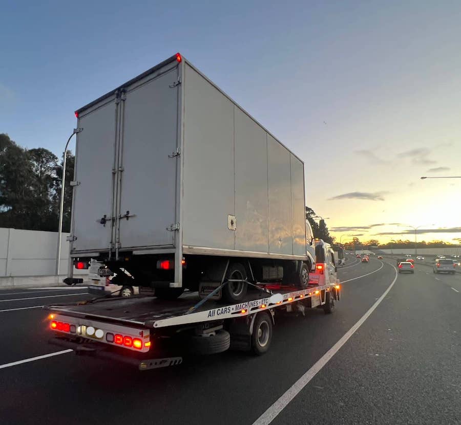 A small truck being transported on the back of a tow truck.