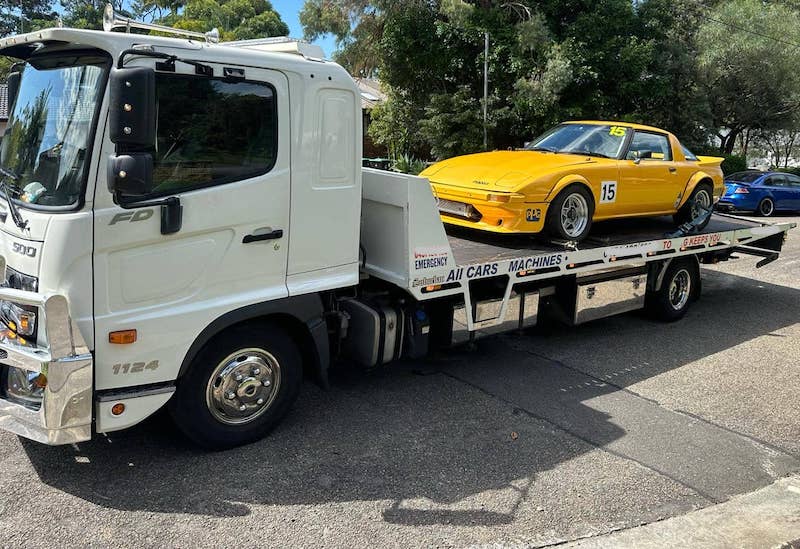 A tilt tray truck towing a car.