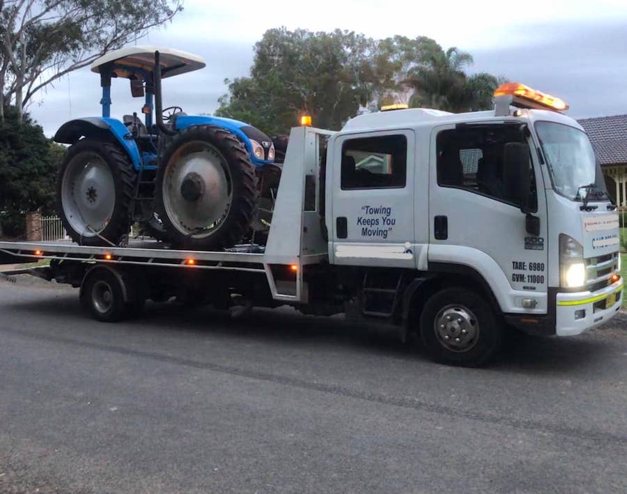 A tow truck towing a heavy tractor.